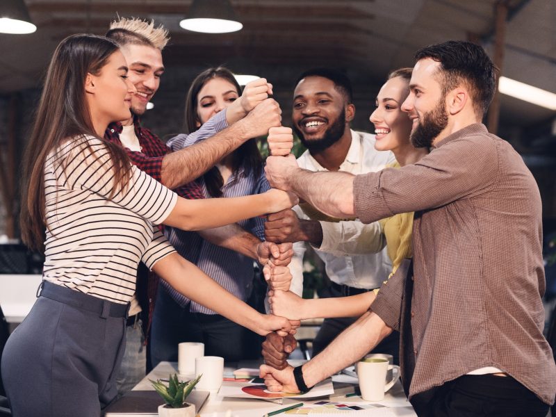 Cooperation and teambuilding concept. Colleagues building tower from fists