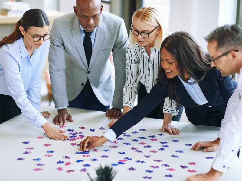 Diverse group of businesspeople working together to solve a puzzle