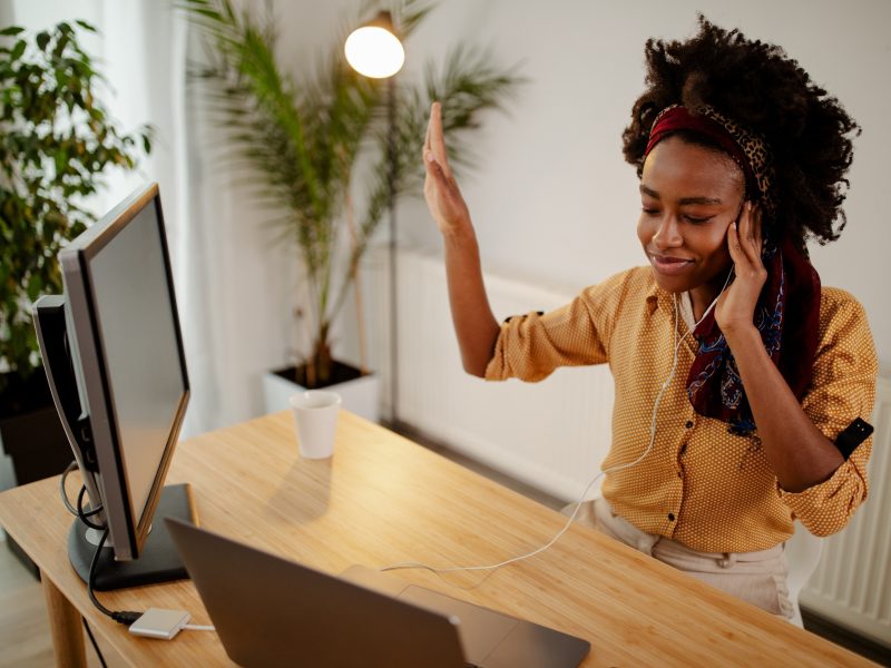 Freelance Afro American girl enjoys music in headphones.